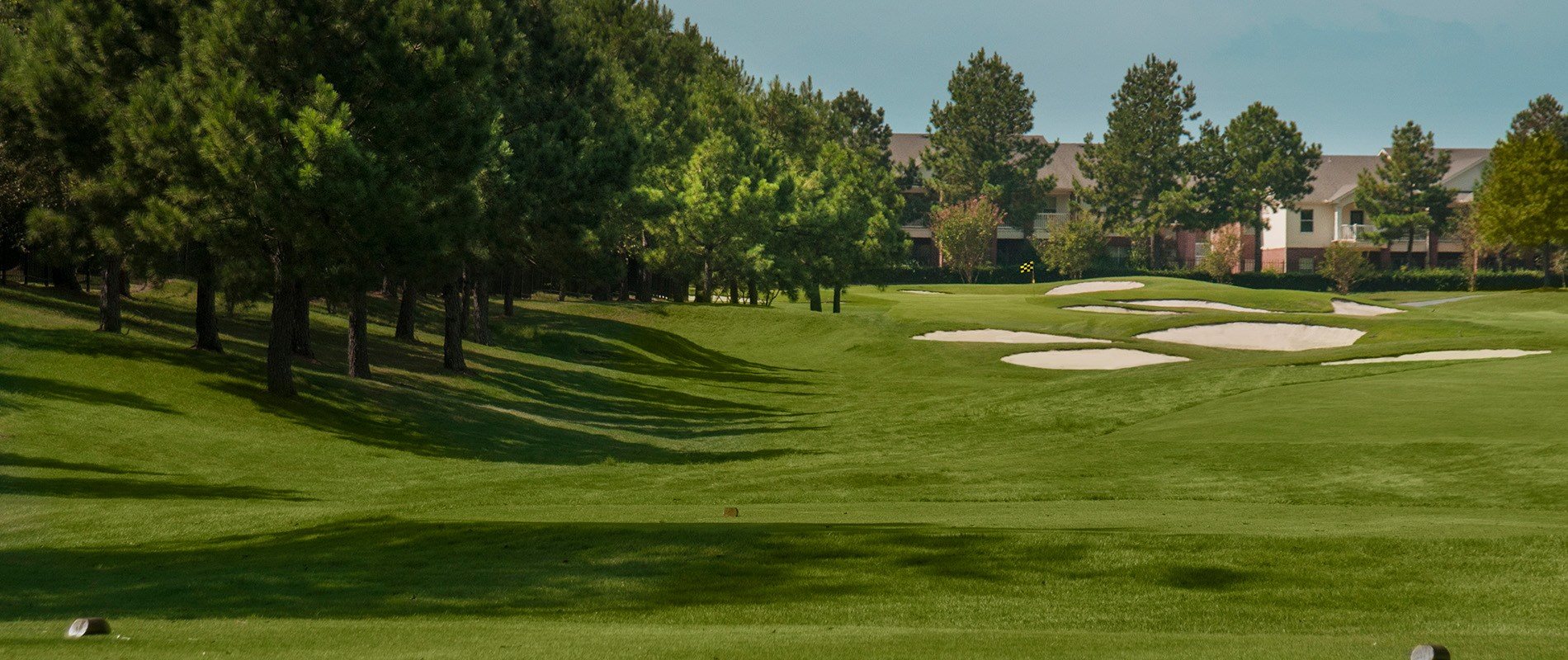 A golf course with a green lawn and trees.